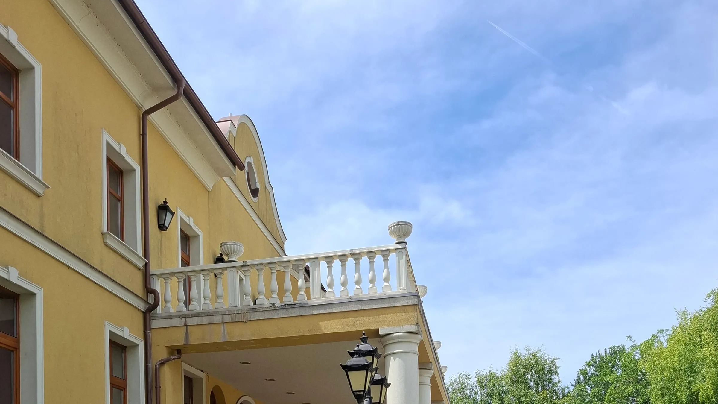 Yellow baroque façade of the manor house with a balcony